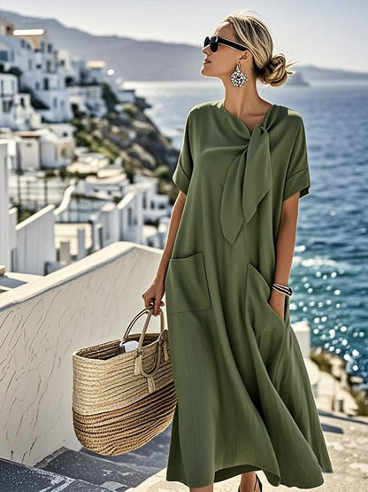 Robe longue en coton vert militaire, manches courtes, grand nœud à l’encolure, poches.