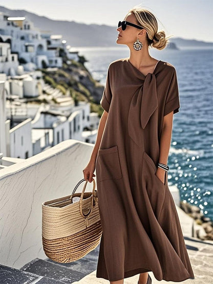 Robe ample en coton marron, manches courtes, nœud au col, poche avant plaquée.