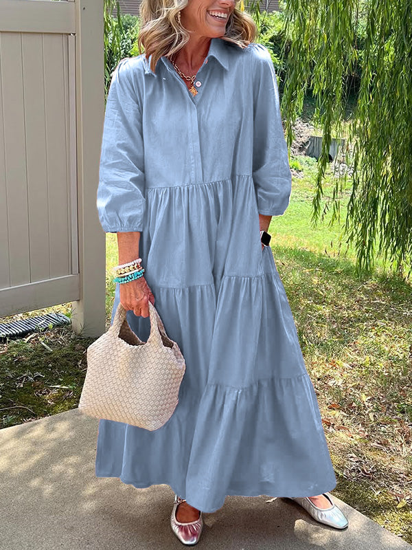 Robe longue bleu clair boutonnée, manches bouffantes, coupe évasée avec volants.