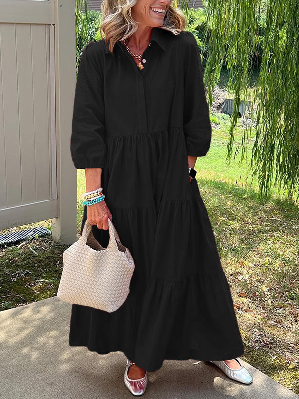 Robe longue noire à col boutonné, manches bouffantes, taille marquée et volants.
