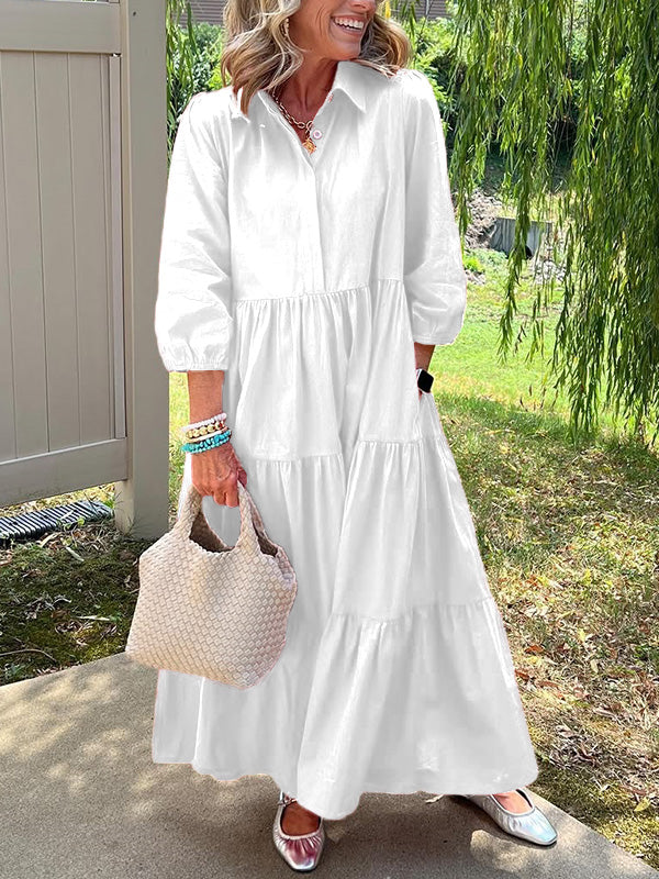 Robe longue blanche à col boutonné, manches bouffantes et jupe évasée à volants.