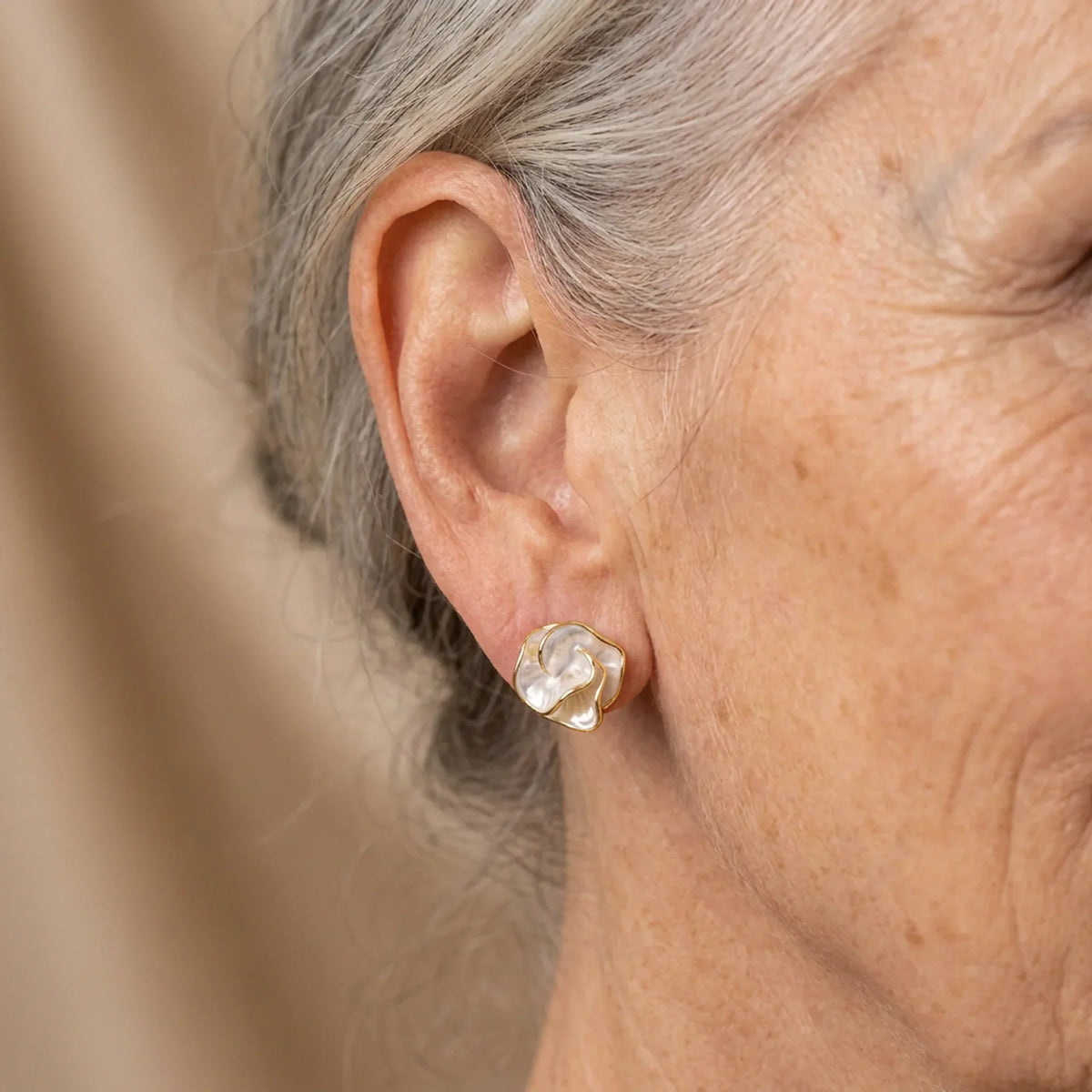 Boucles d’oreilles en perles blanches en forme de fleur, portées sur l’oreille