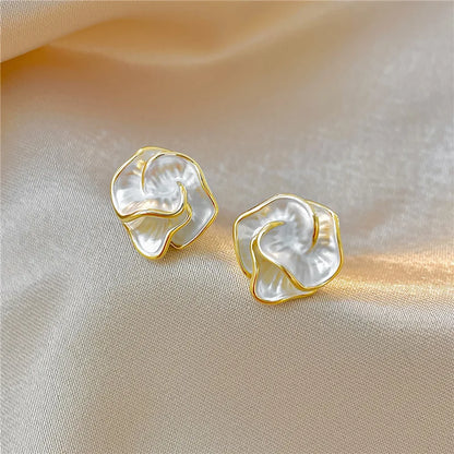 Boucles d’oreilles fleur en perle blanche avec contour doré, vue rapprochée