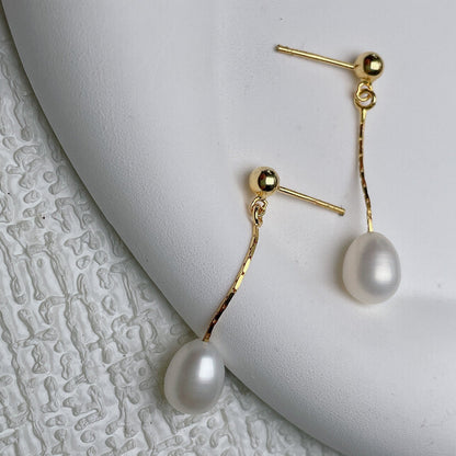 Boucles d’oreilles dorées à perle blanche pendante, fermoir à tige.
