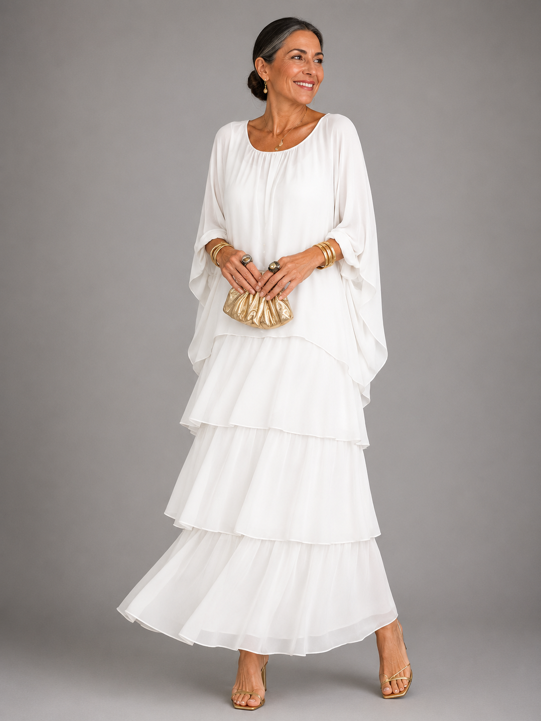 Robe longue fluide blanche à volants étagés, manches chauve-souris, encolure ronde.