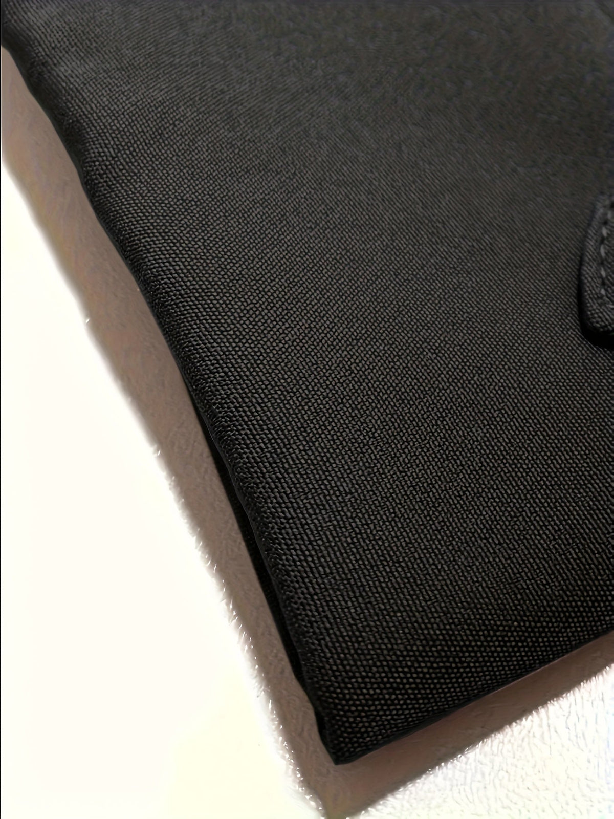 Échantillon de tissu noir à texture serrée, bord cousu