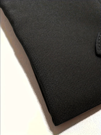 Échantillon de tissu noir à texture serrée, bord cousu