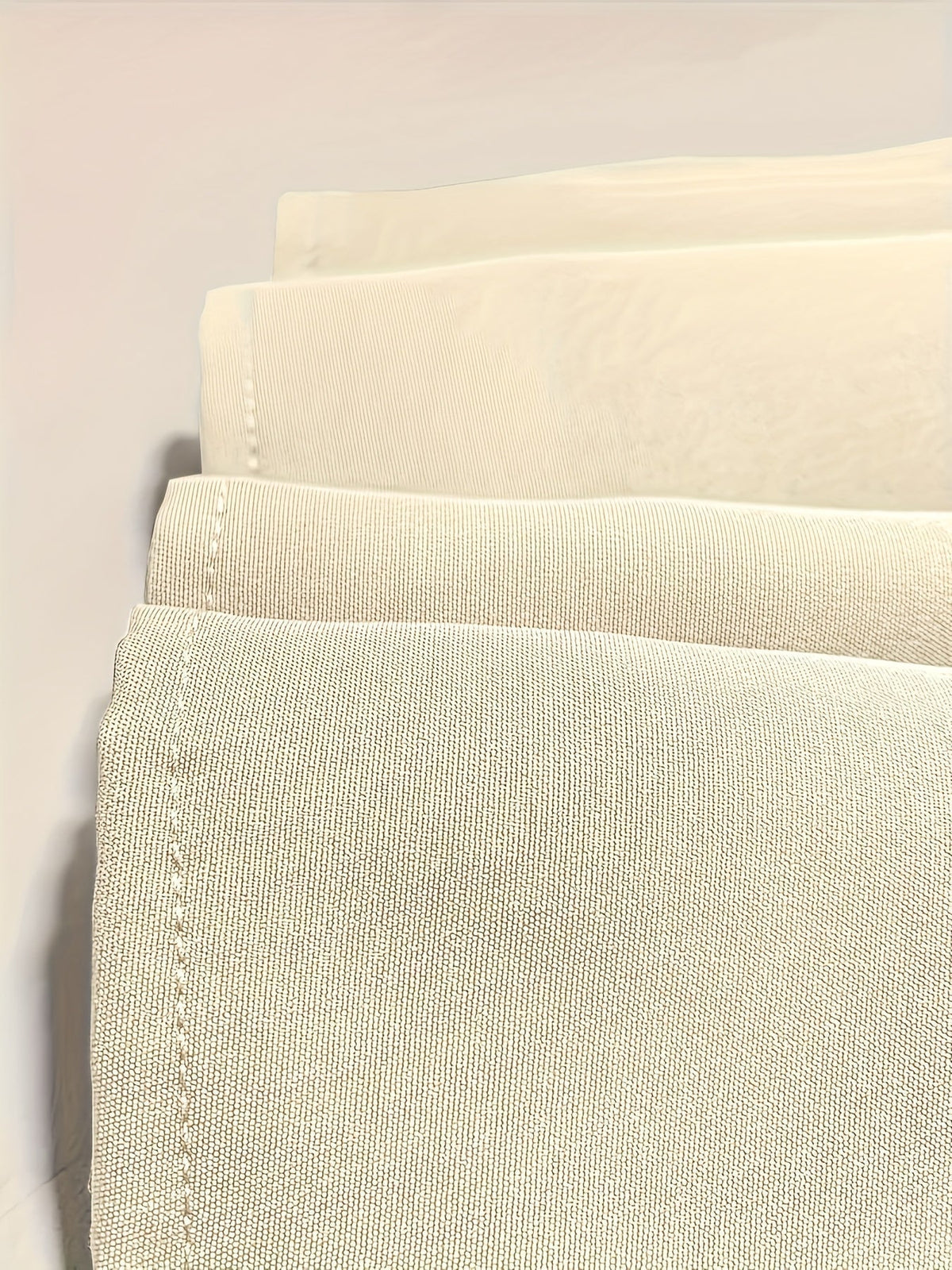 Échantillons de tissu beige clair, bord surpiqué et texture tissée