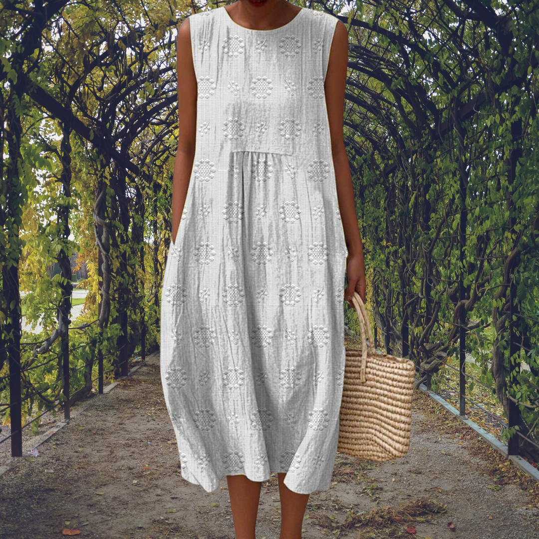 Robe sans manches blanche à broderies, encolure ronde et jupe ample à volants.