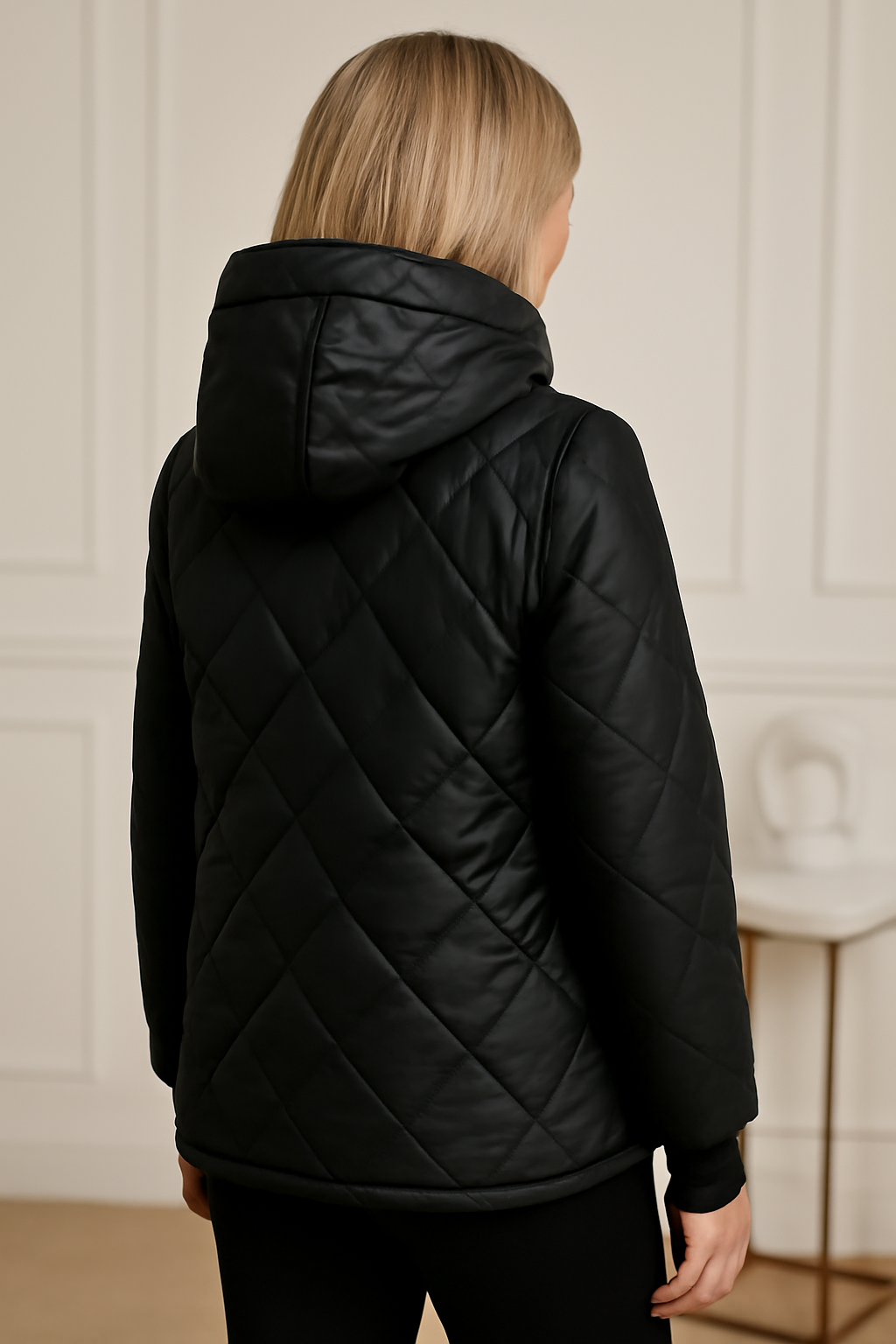 Veste matelassée noire à capuche, surpiqûres losanges, dos visible.
