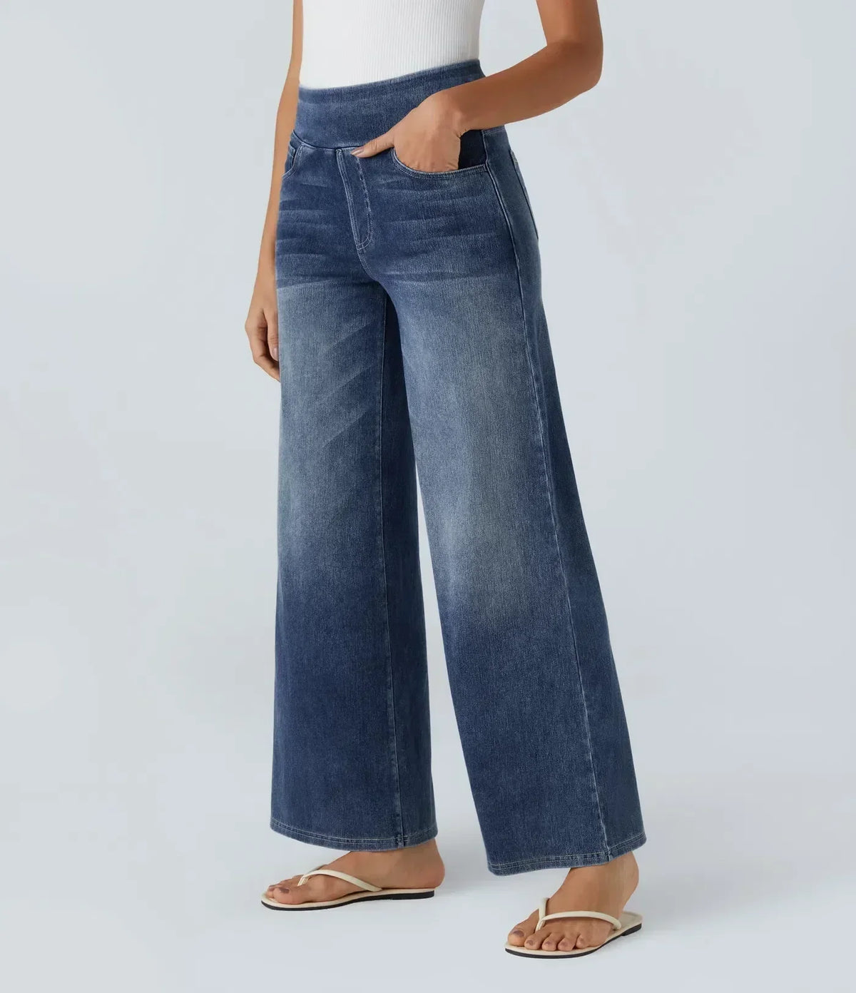 Pantalon en jean bleu foncé à coupe large, taille élastique, poches avant visibles.