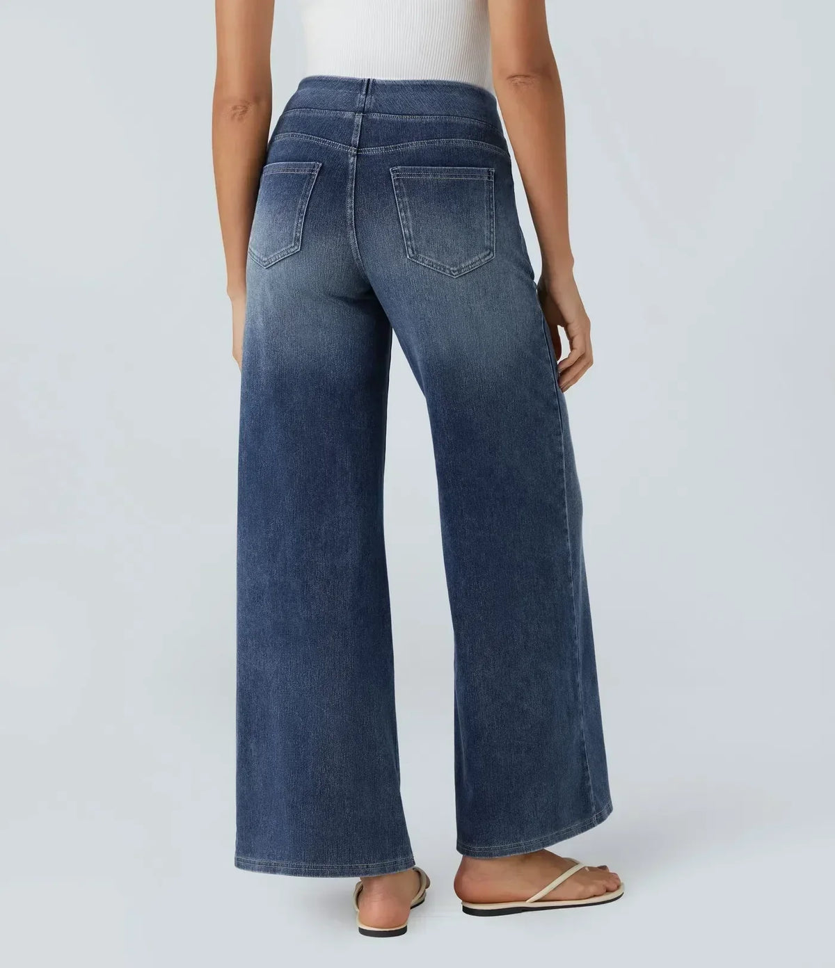 Pantalon en jean bleu foncé coupe évasée, surpiqûres et poches arrière visibles.