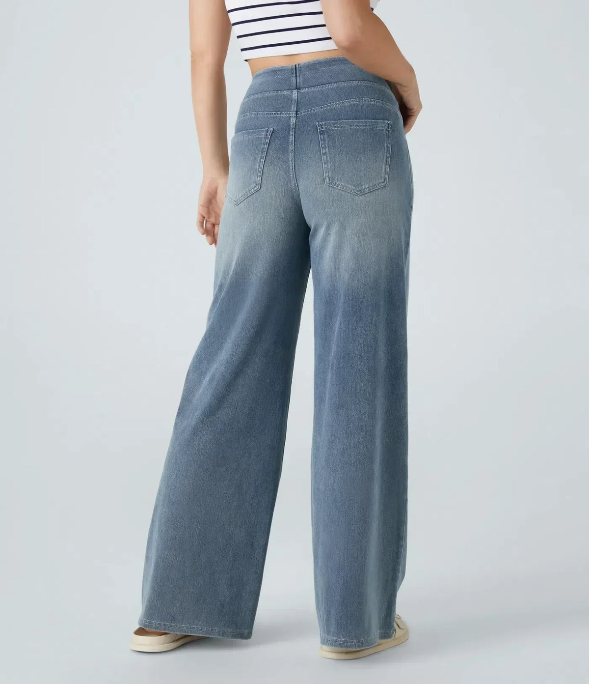 Pantalon en jean bleu clair, dos avec poches arrière et surpiqûres visibles.