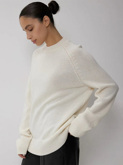 Pull en cachemire crème, col rond côtelé, manches longues, porté sur un côté