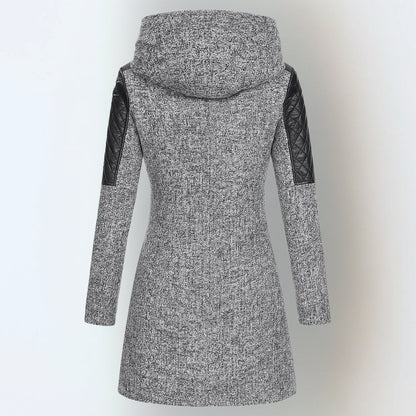 Manteau d’hiver gris chiné à capuche, manches matelassées noires, coupe longue droite.