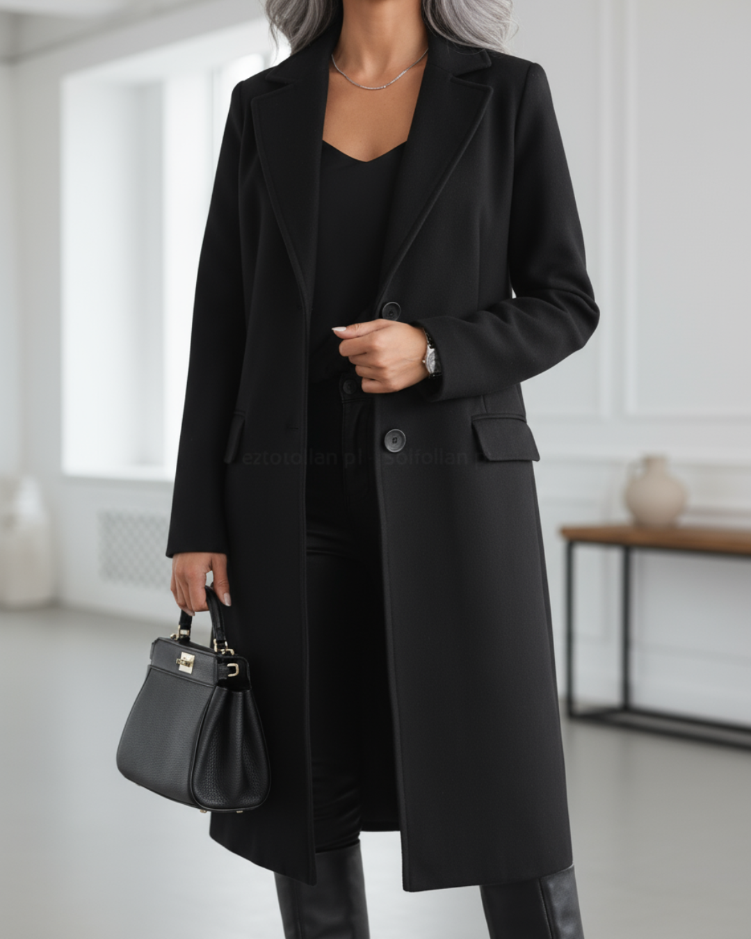 Manteau long noir à revers, fermeture boutonnée, poches plaquées.