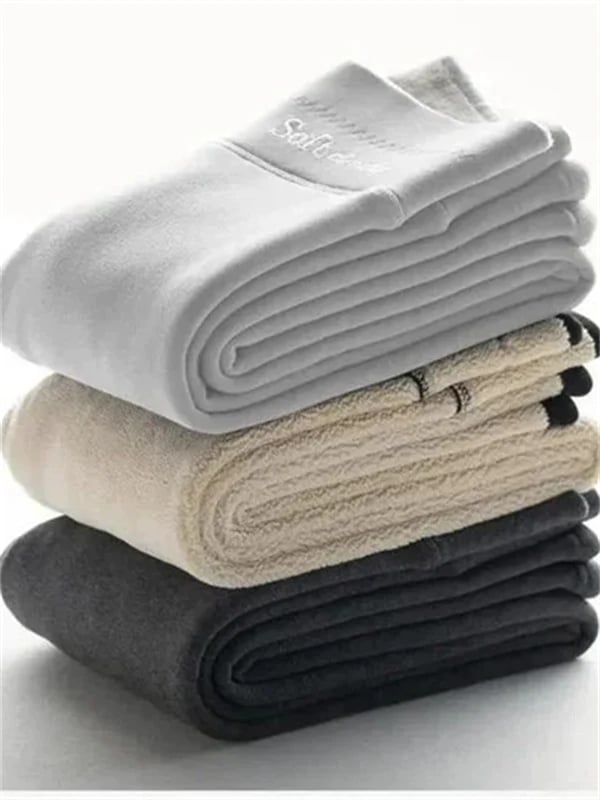 Piles de leggings d’hiver doublés, tons gris, blanc et noir, tissu épais.