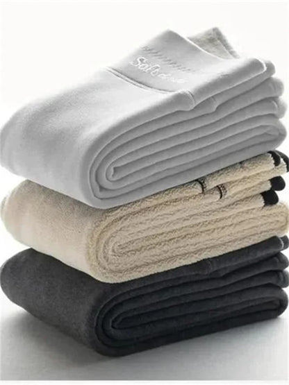 Piles de leggings d’hiver doublés, tons gris, blanc et noir, tissu épais.
