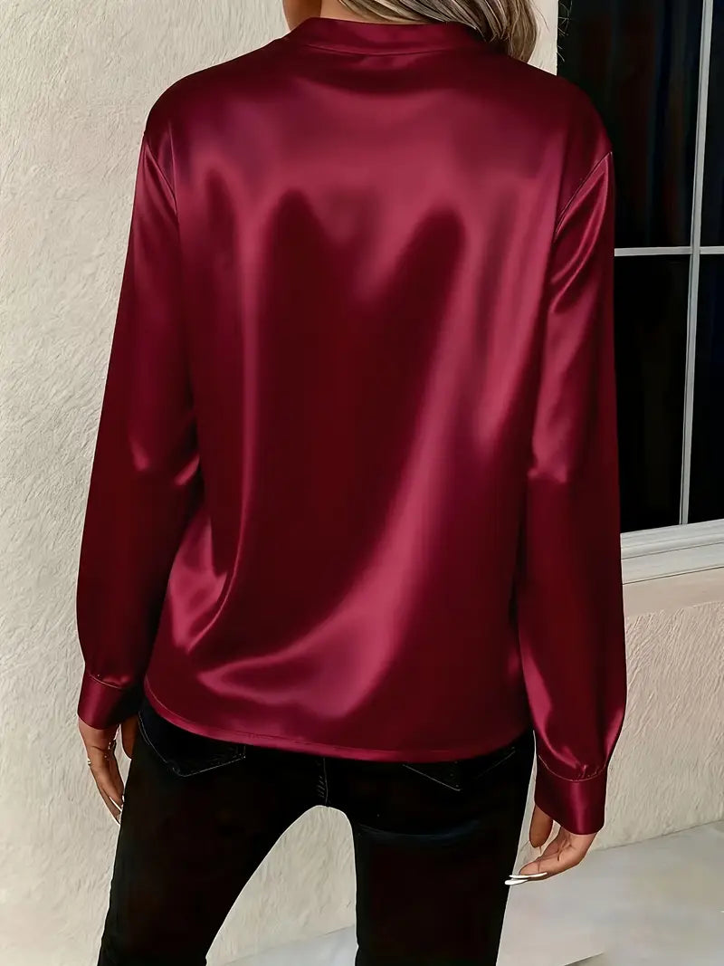 Chemisier en satin bordeaux à col V et manches longues, coupe fluide.