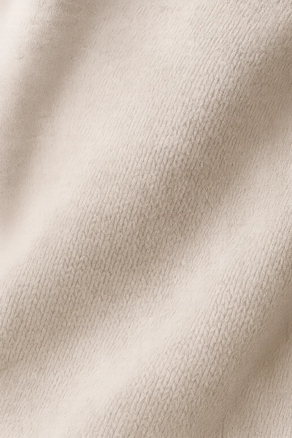 Détail de maille texturée de robe tricotée beige, surface fine et tissée.