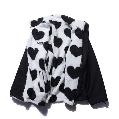 Veste réversible enfant en polaire blanche à cœurs noirs, capuche et zip visibles.