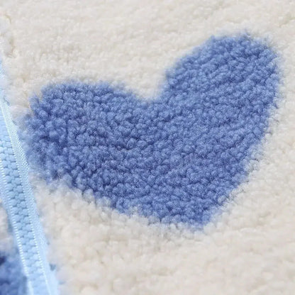 Détail tissu polaire : motif cœurs bleus sur fond écru, fermeture éclair visible.