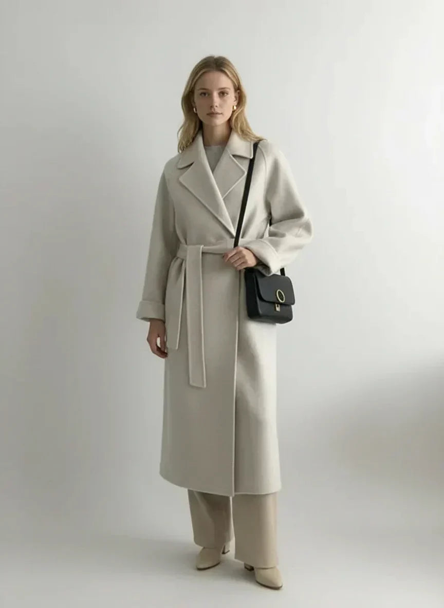 Manteau long écru à col revers, ceinture nouée, poches et fente centrale