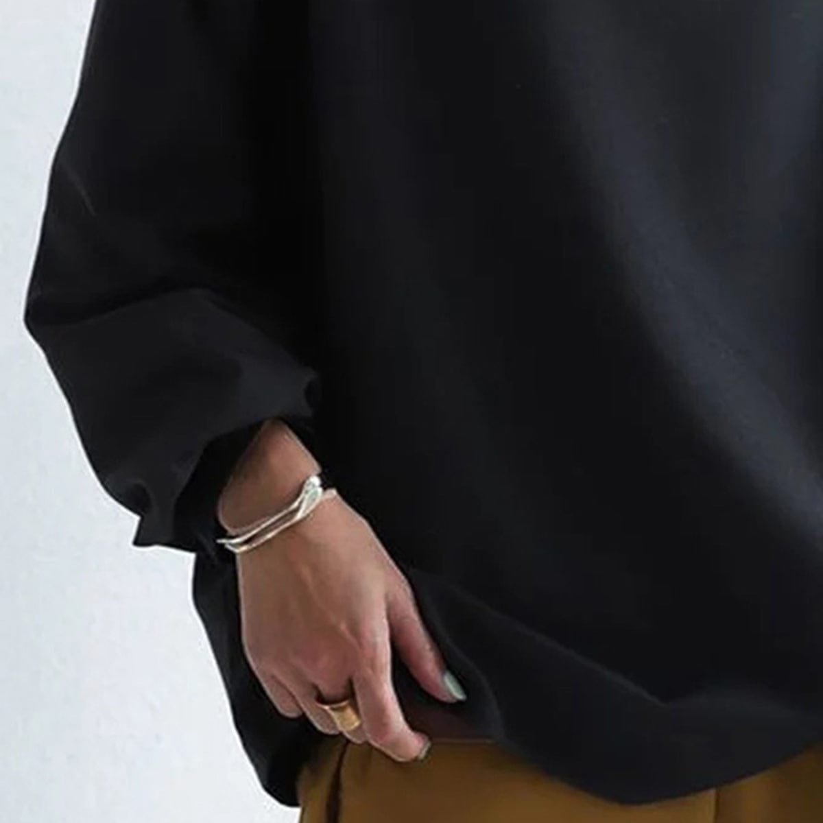 Haut noir à manches bouffantes, gros plan sur la couture et le poignet