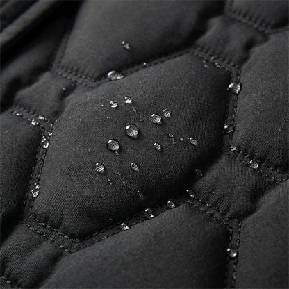 Manteau long imperméable noir matelassé, gouttes d’eau visibles sur les coutures.