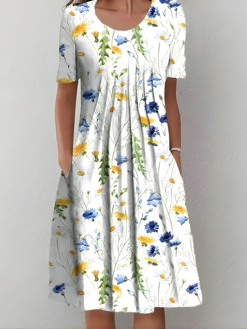 Robe plissée blanche à fleurs jaunes et bleues, manches courtes, encolure ronde.