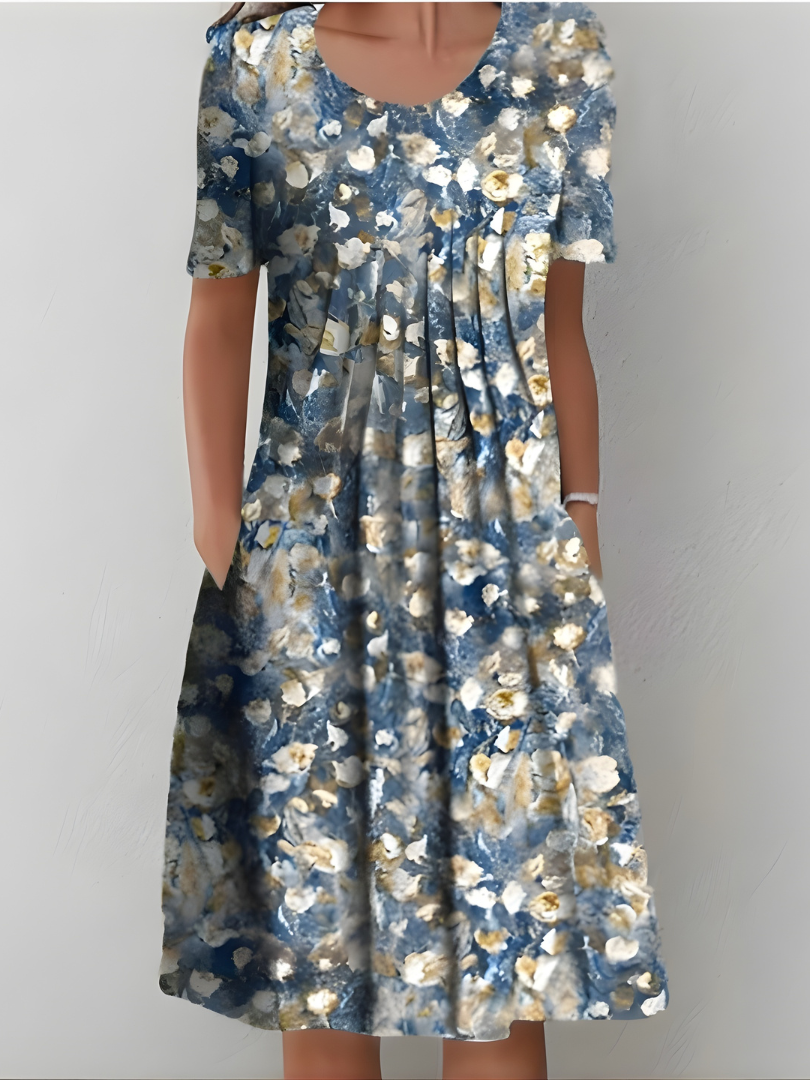 Robe plissée bleu nuit à fleurs blanches et beiges, manches courtes, encolure ronde.