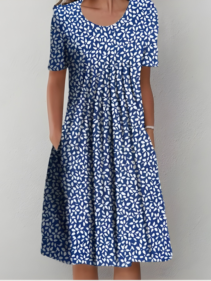 Robe plissée bleue à motifs blancs irréguliers, manches courtes, encolure ronde.