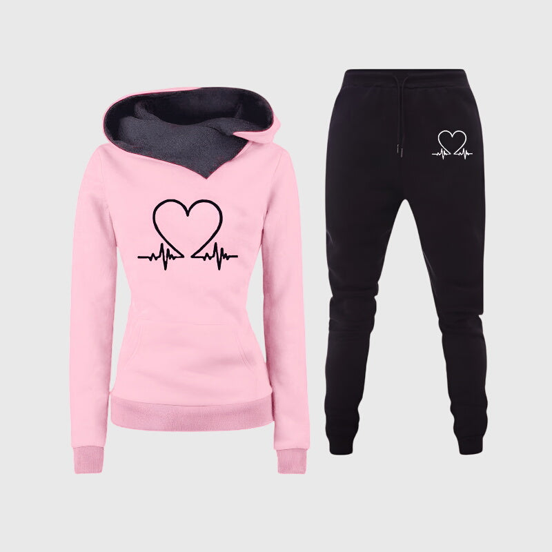 Ensemble sweat à capuche rose et jogging noir, motif cœur avec ligne de rythme cardiaque.