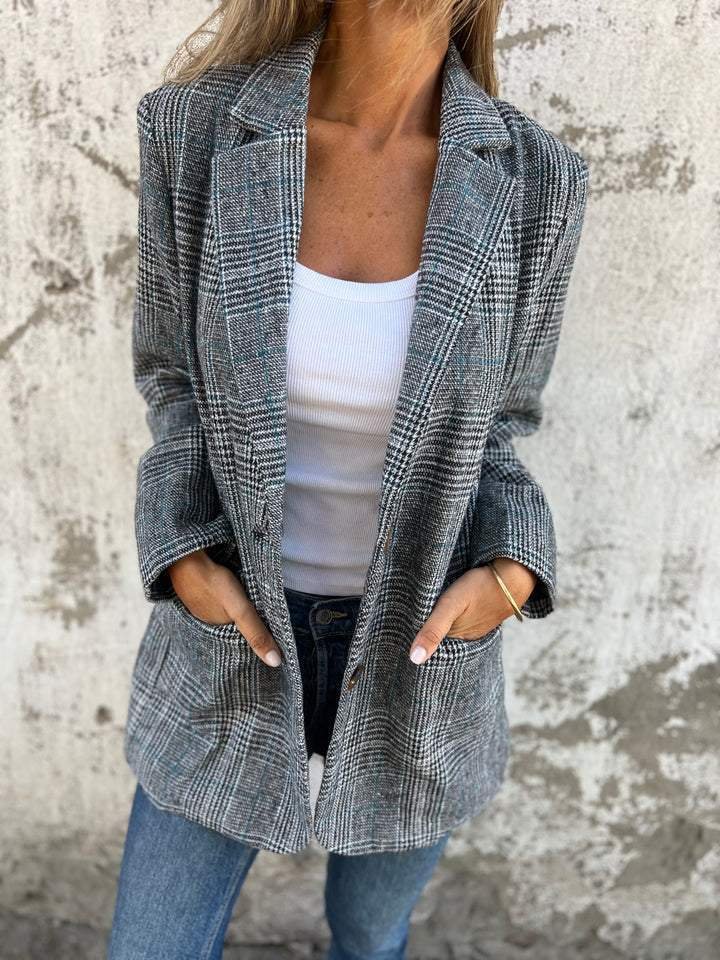 Manteau à carreaux gris avec col châle, boutonnage devant, poches plaquées.