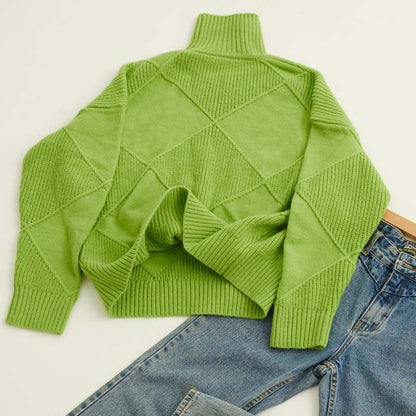 Pull en tricot vert à col roulé, motifs torsadés en losanges, posé à plat