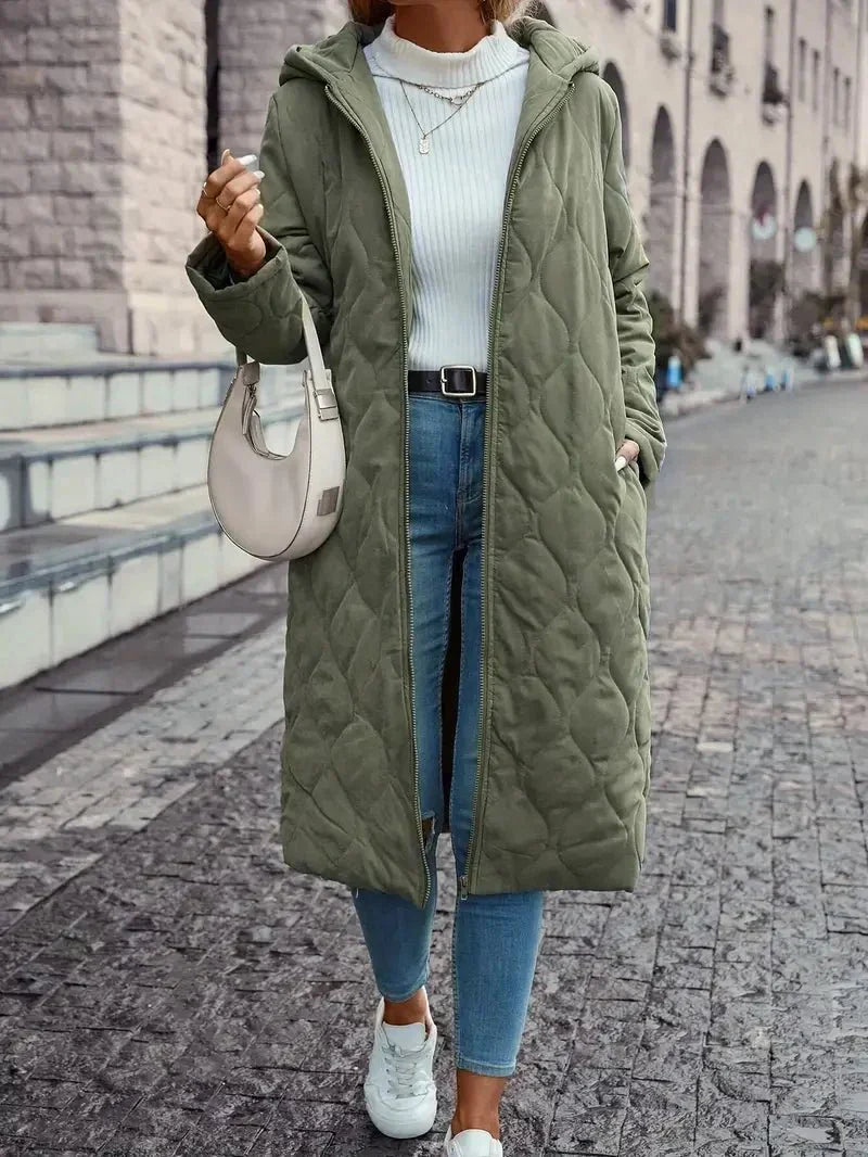 Manteau long matelassé vert à capuche, fermeture zippée, coutures visibles, poches.