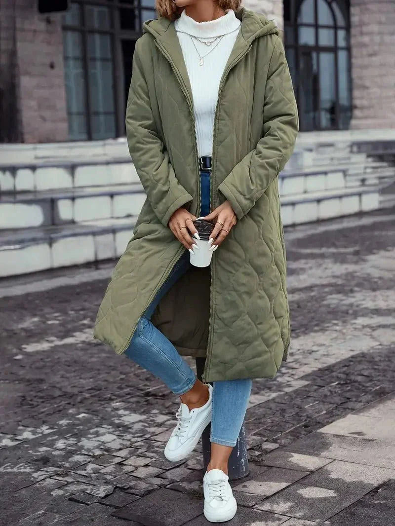 Manteau d’hiver vert matelassé à capuche, fermeture zippée, doublure beige visible.