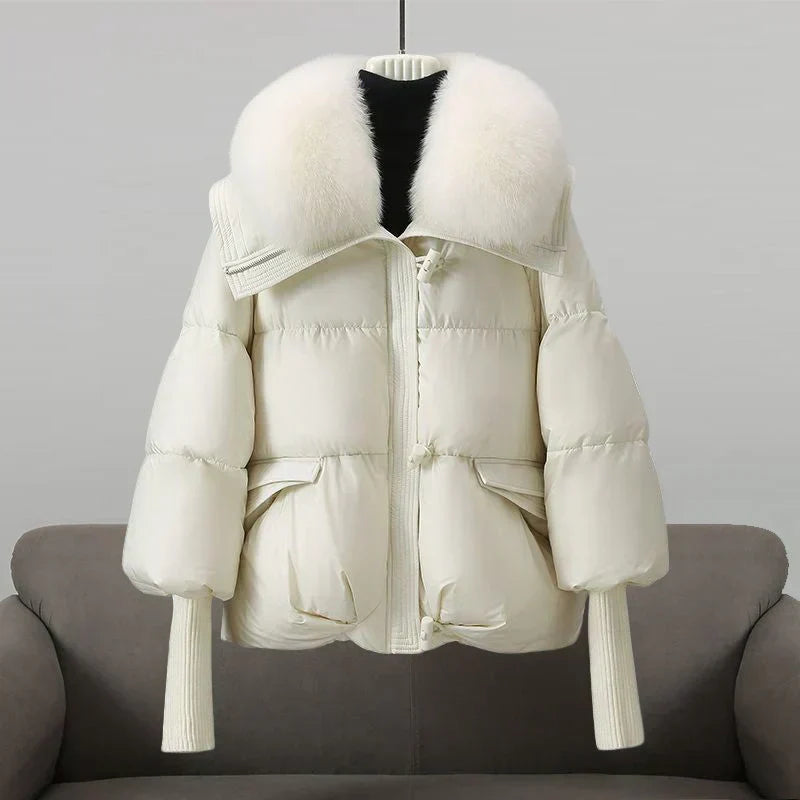 Manteau matelassé blanc à capuche bordée de fourrure, zip et poches à rabat.