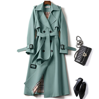 Trench-coat vert bouteille avec col pointu, ceinture réglable et boutons noirs, doublure à carreaux.