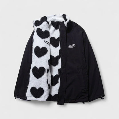 Veste réversible : face polaire à cœurs noir et blanc, revers en tissu noir.