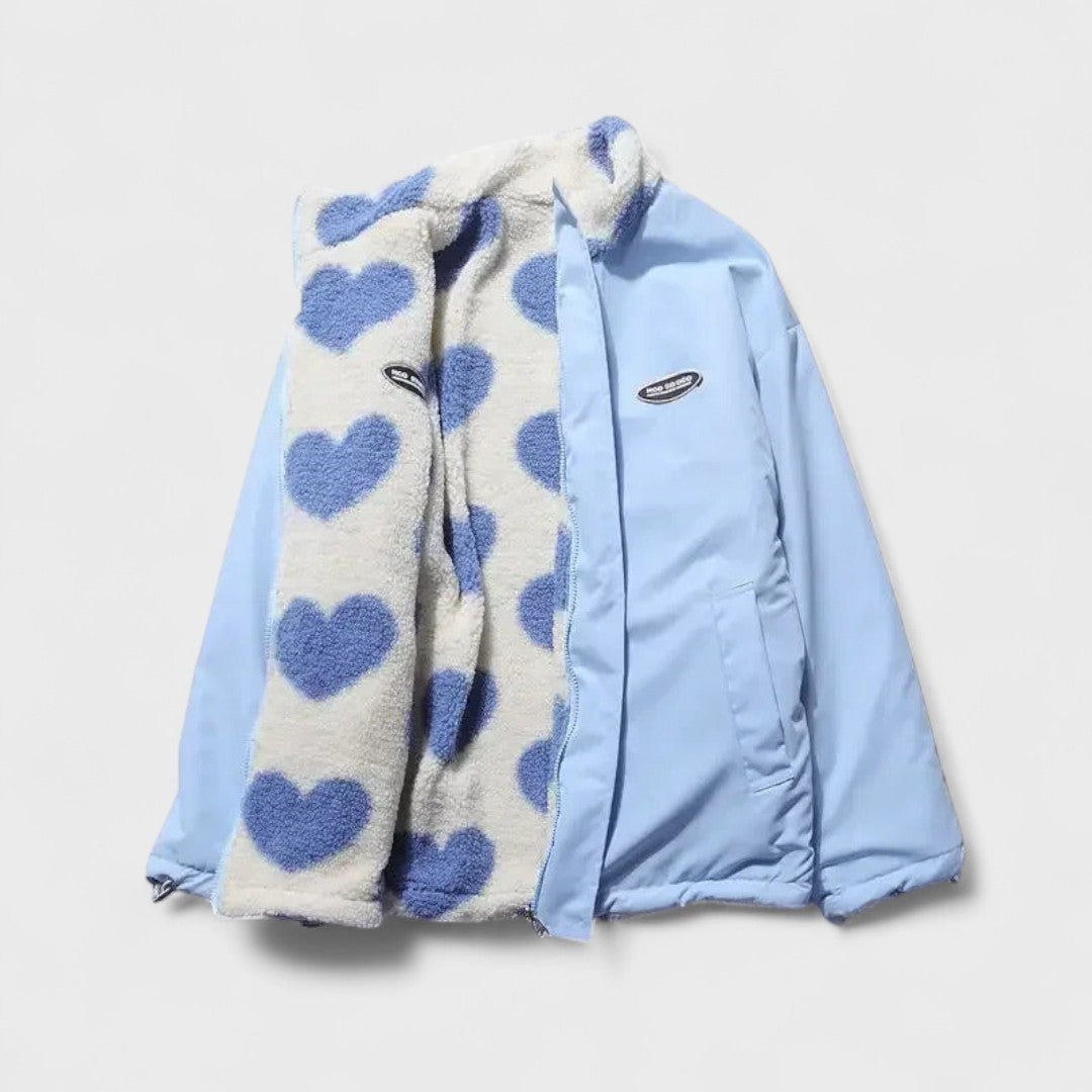Veste réversible : face polaire à cœurs bleu et fond clair, revers en tissu bleu clair.