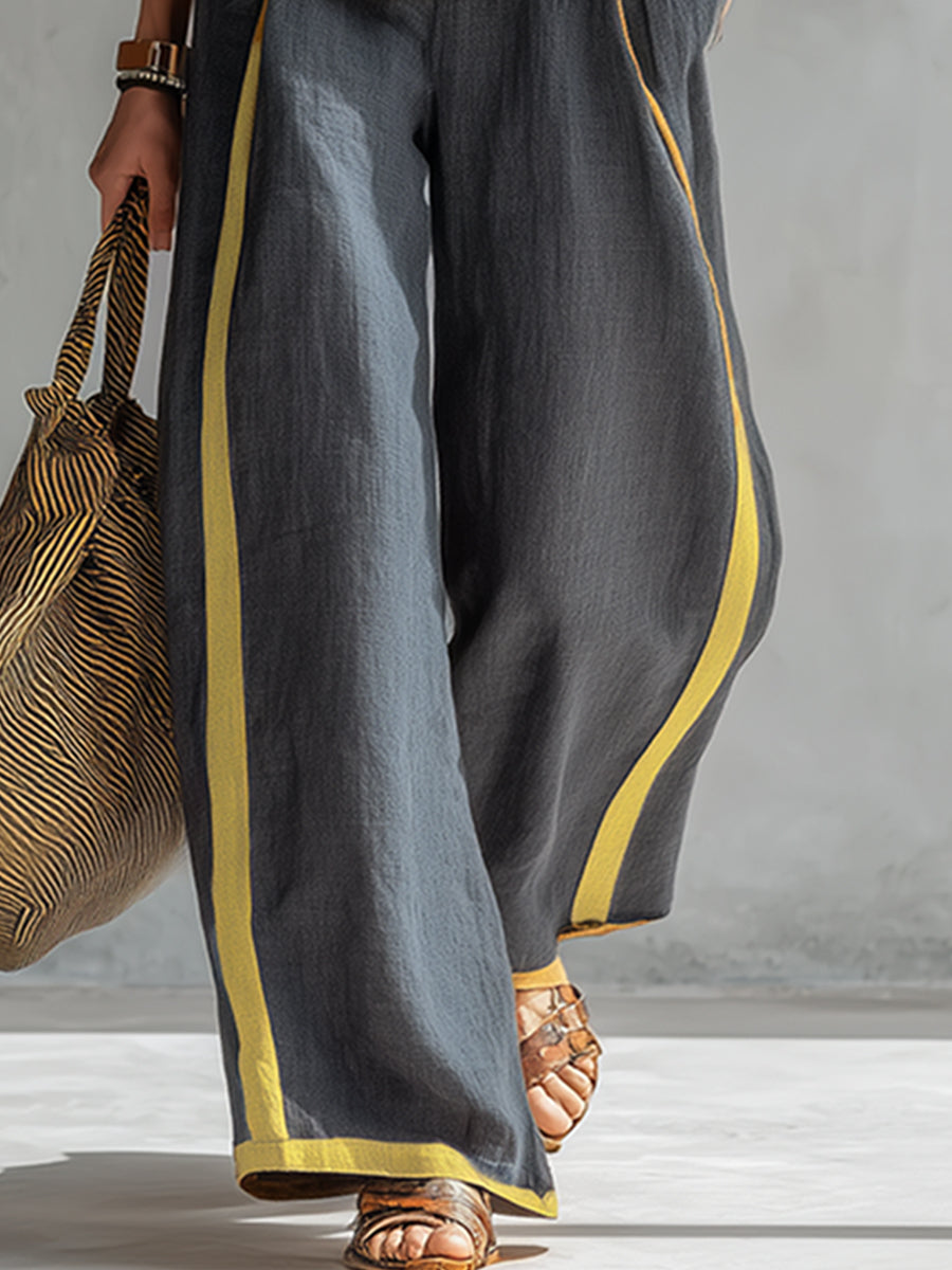 Pantalon ample bleu marine à passepoil jaune, vue rapprochée sur la jambe et l’ourlet