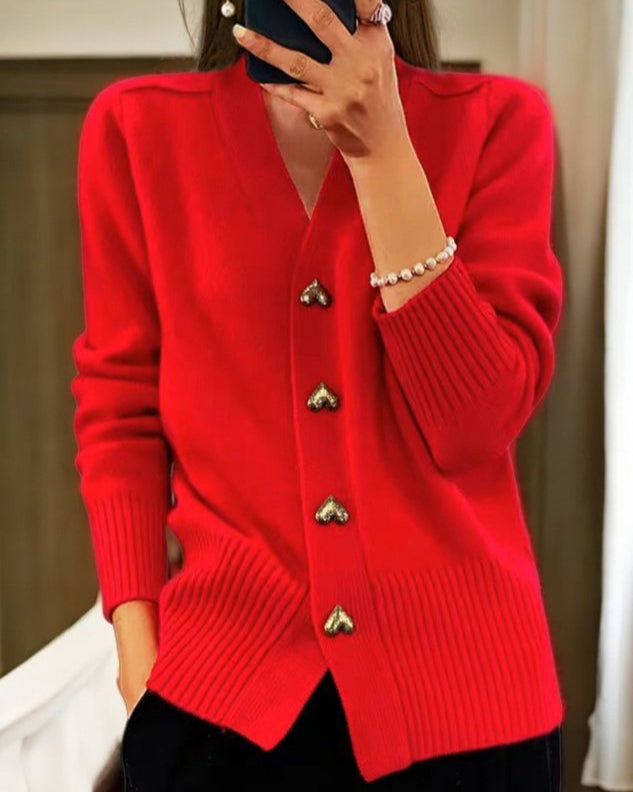 Gilet doux rouge à encolure en V, boutons en forme de cœur dorés, manches longues.