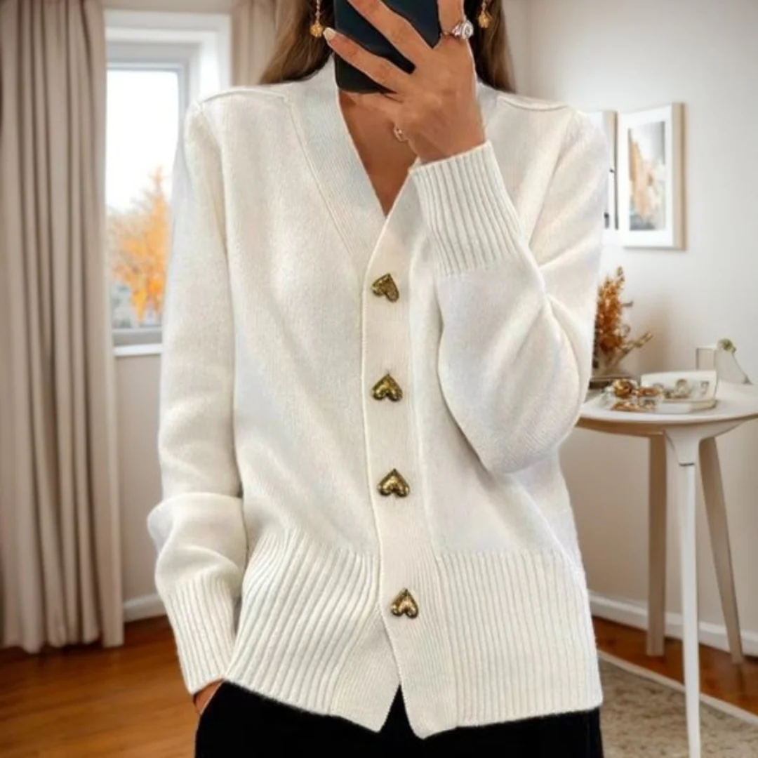 Gilet doux blanc cassé à encolure en V, boutons en forme de cœur dorés, manches longues.