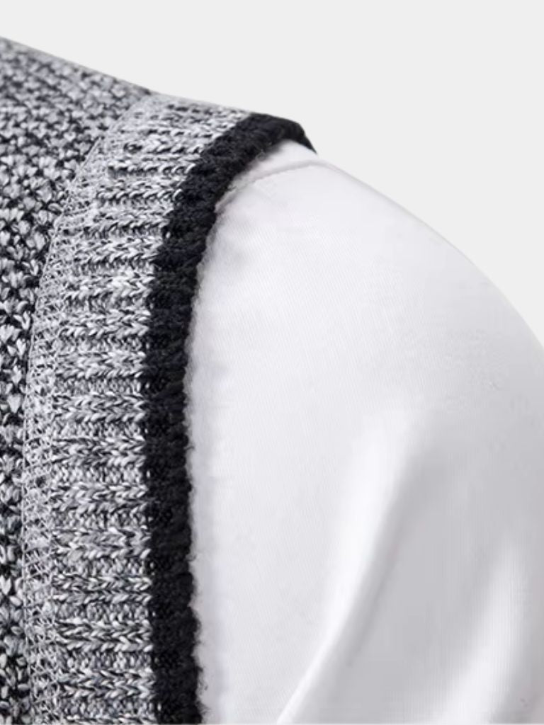Gilet gris à bord noir, maille texturée, empiècement d’épaule visible.