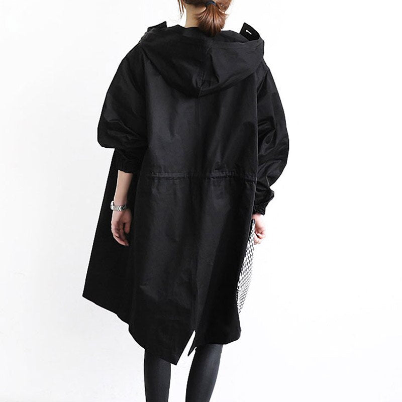 Trench-coat déperlant long noir à capuche, patte boutonnée, coupe évasée.