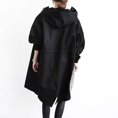 Trench-coat déperlant long noir à capuche, patte boutonnée, coupe évasée.