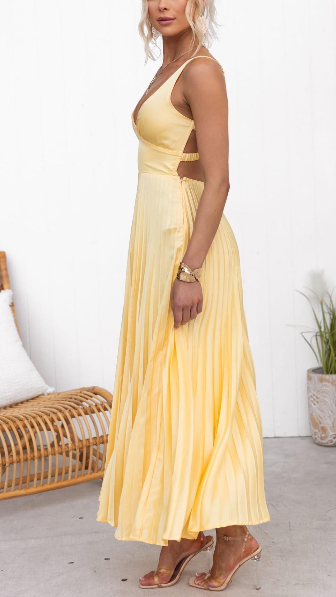 Robe longue plissée jaune à bretelles fines, coupe près du corps.
