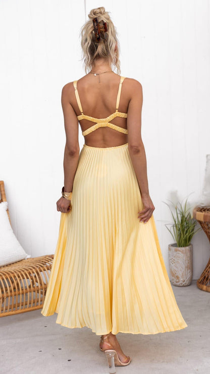 Robe longue plissée jaune, dos nu avec bretelles croisées et lien au cou.