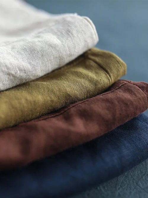 Blouse en lin vert olive pliée, texture visible du tissu et superposition de couleurs.